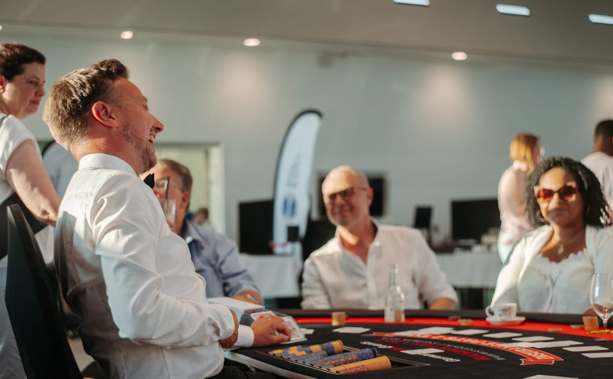 Lachender Croupier mit Gästen am Blackjack-Tisch